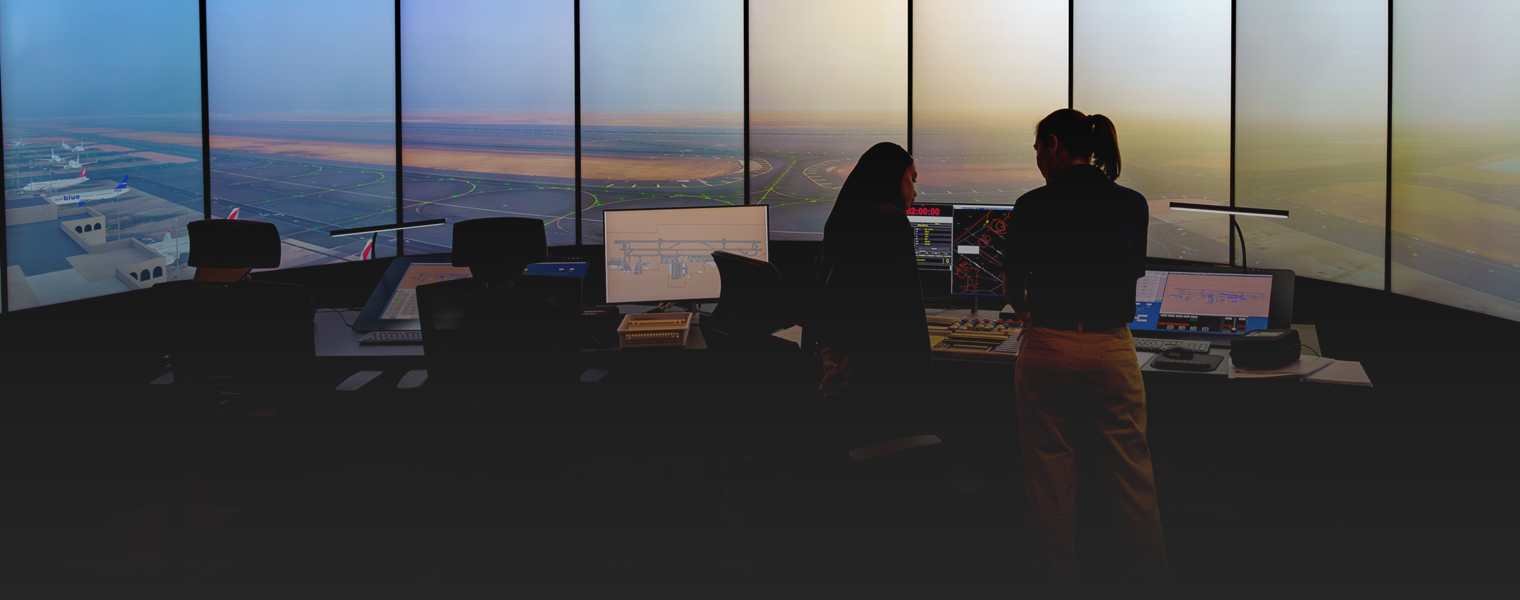 Two women stood in front of screens inside the air traffic control simulator.